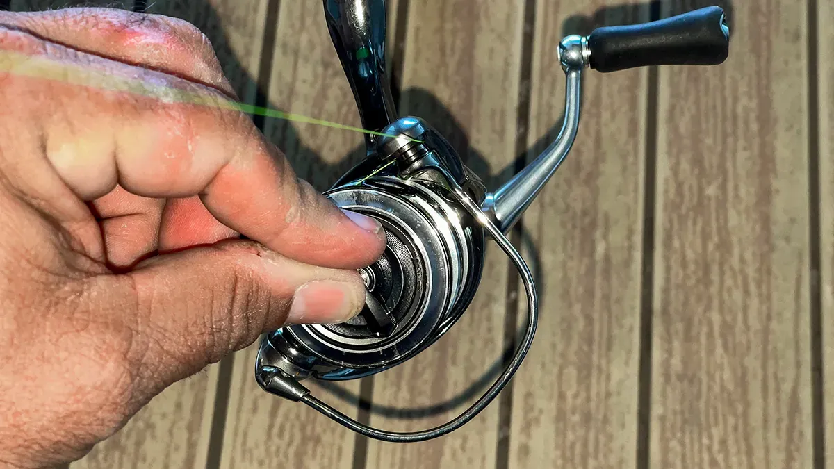 Hands adjusting fishing reel drag system