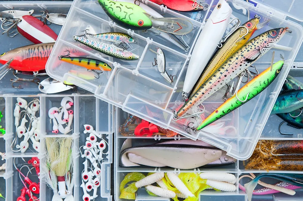 Selection of pike lures including spinnerbaits, jerkbaits, and soft plastics arranged on tackle box