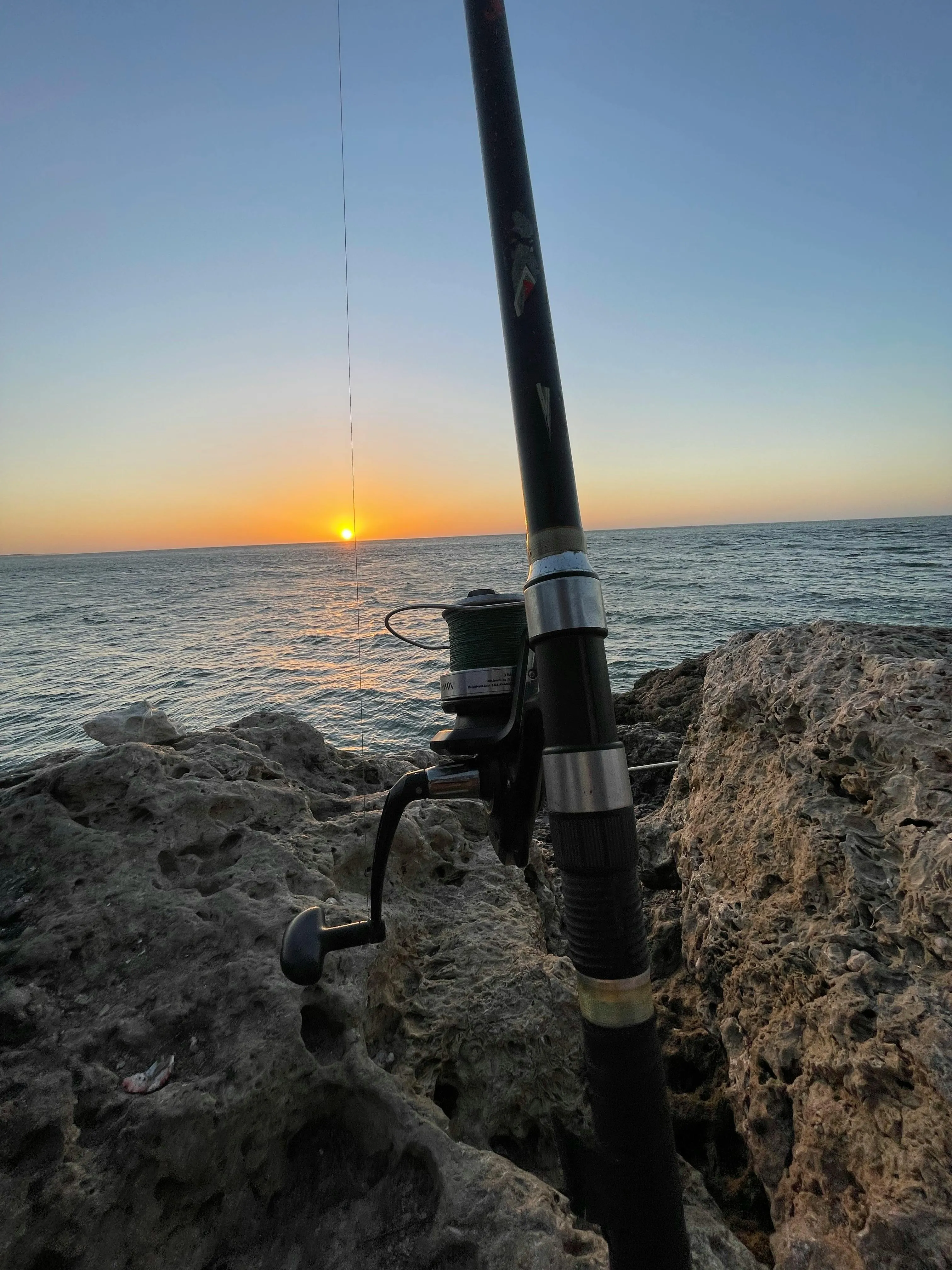 Fishing rod secured on rocky shoreline with proper anchoring